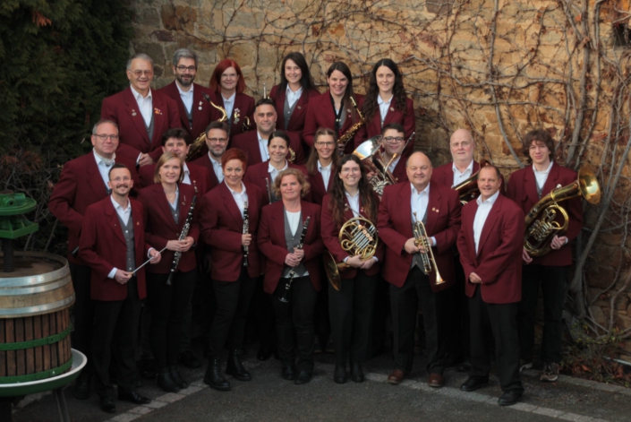 Blasorchester mit neuem Dirigent Bild Blasorchester in Rot vor einer Mauer